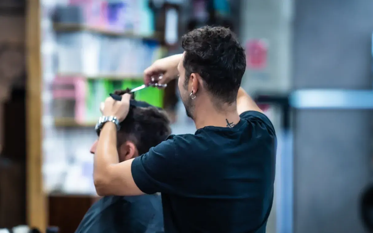 Peluquero corta el pelo a un persona.